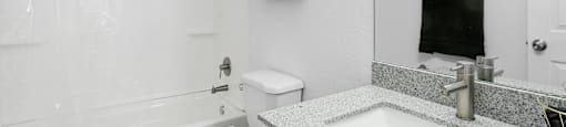 A white toilet sits next to a white bathtub in a bathroom.