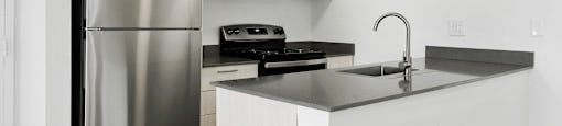A modern kitchen with a stainless steel refrigerator and black countertops.
