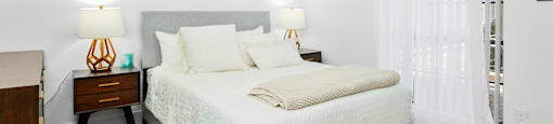 A bedroom with a bed, nightstands, and pictures on the wall.