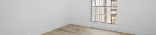 A room with a window and wooden flooring.