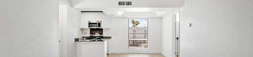 A kitchen with white cabinets and a wooden floor.