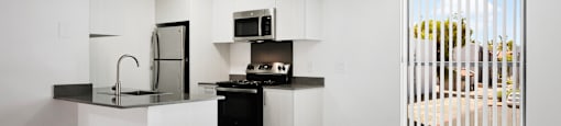 A modern kitchen with white cabinets and a black countertop.