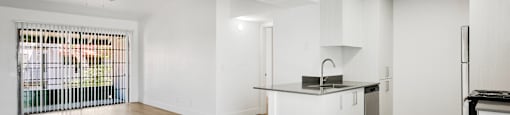 A kitchen with white cabinets and a wooden floor.