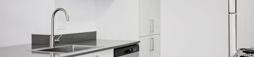 A modern kitchen with white cabinets and a stainless steel sink and dishwasher.