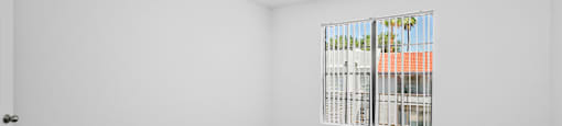 A room with a ceiling fan and a window showing a view of a building.