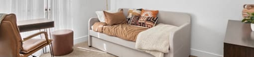 A living room with a white couch and a brown chair.