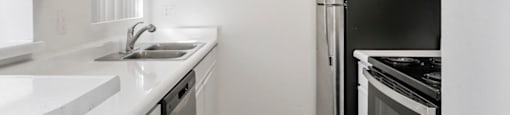 A kitchen with white cabinets and a black refrigerator.