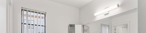 A white bathroom with a window and a sink.