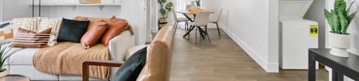 A living room with a couch, a chair, a table, and a potted plant.