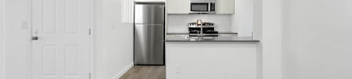 A kitchen with a refrigerator, microwave, and oven.