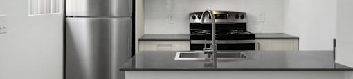 A kitchen with a stainless steel refrigerator and microwave above a counter.