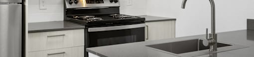 A modern kitchen with a stainless steel refrigerator, black stove, and a black microwave above the stove.