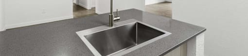 A modern kitchen with a stainless steel sink and a large mirror.