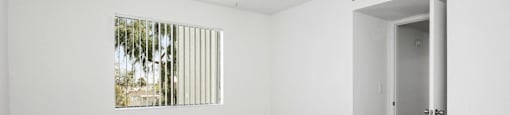 A room with a ceiling fan and a door leading to another room.