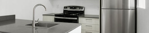 A modern kitchen with a stainless steel refrigerator, microwave, and oven.