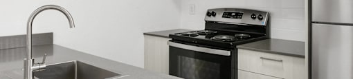 A modern kitchen with a stove, sink, and refrigerator.