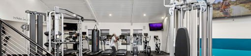 a gym with weights and cardio equipment and a staircase