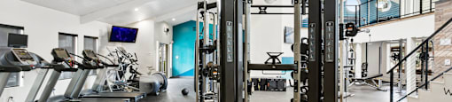 a gym with cardio equipment and weights on the floor