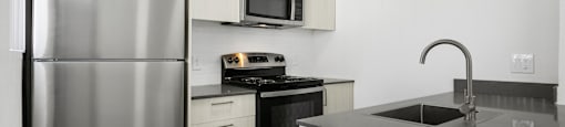 A modern kitchen with a stainless steel refrigerator and black countertops.