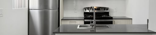 A kitchen with a stainless steel refrigerator and microwave above a counter.