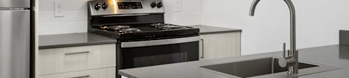 A modern kitchen with a stainless steel refrigerator, black stove, and a black microwave above the stove.