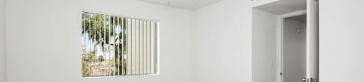 A room with a ceiling fan and a window with blinds.