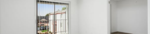 A room with a sliding glass door leading to a balcony.