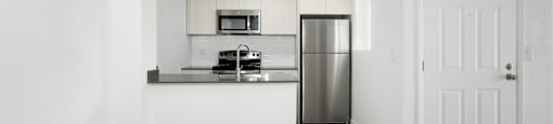 A kitchen with a refrigerator, microwave, and oven.