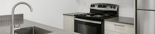 A modern kitchen with a stove, sink, and refrigerator.