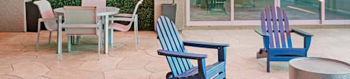 a patio with a table and chairs and a green hedge