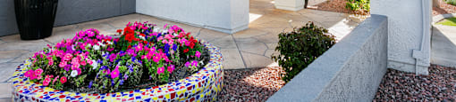 a white building with a red roof and a large planter with colorful flowers