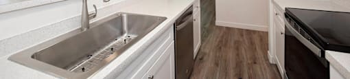 A kitchen with a stainless steel sink and white cabinets.