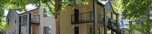 A tree in front of a two-story building.