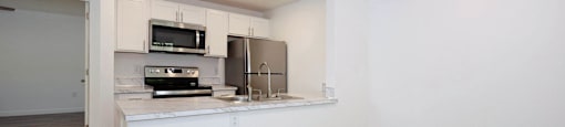 A kitchen with white cabinets and a wooden floor.