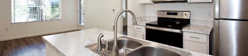 A modern kitchen with a marble countertop and stainless steel appliances.
