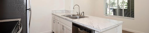 A kitchen with a black fridge and a white counter top.