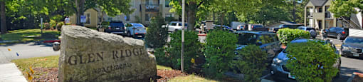 A sign for Glen Ridge apartments is in front of a parking lot.