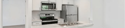 A kitchen with white cabinets and a wooden floor.
