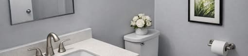 A bathroom with a toilet, sink, and pictures on the wall.