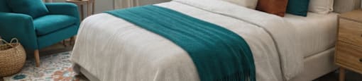 A bedroom with a large bed, a blue chair, and a rug.