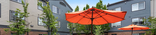 Dog-Friendly Apartments in Federal Way WA - Meridian Court - Multiple Seating Area, Planted Garden, Umbrella Shaded Areas, and Building Exterior