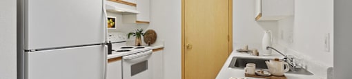 Kitchen with a white refrigerator freezer next to a stove top oven at Lakewood Meadows Apartments in Lakewood, WA