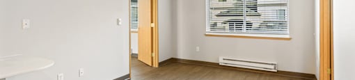 Retirement Homes In Federal Way - Spacious Living Room With New Wood-Style Plank Flooring, Ceiling Fan, Fresh Paint, And Window.