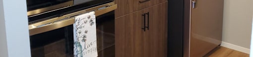 A kitchen with a black fridge and stainless steel appliances.
