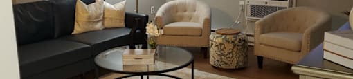 A living room with a black couch, a coffee table, and a lamp.