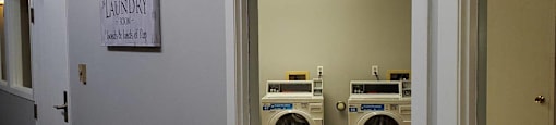 A laundry room with a sign and two washing machines.
