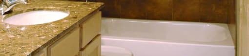 A bathroom with a brown tile wall and a white toilet at Centre Place Apartments, TX, 76205