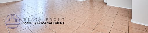 A spacious room with a logo for Beach Front Property Management on the floor.