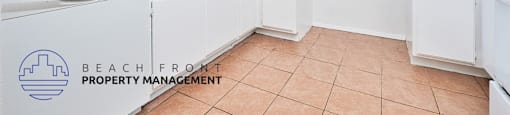 A kitchen with white cabinets and a tile floor.