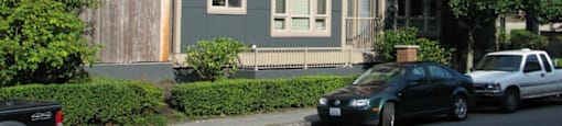 A black car is parked in front of a red and grey building.